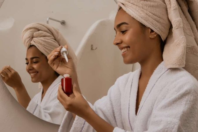 Une femme applique un sérum dans le cadre de sa routine beauté.