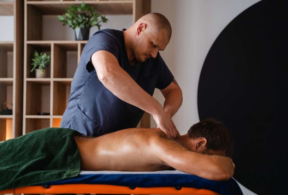 Praticien effectuant un massage décontracturant après la musculation sur le dos d'un homme allongé.